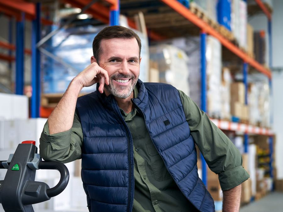 Dueño de una bodega sonriendo junto a su transpaleta
