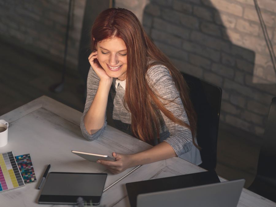 Empresaria sonriendo mientras revisa una tablet en su escritorio